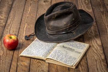 Wall Mural - Vintage expedition journal on a rustic picnic table with an apple and oilskin hat. Travel log from paddling trip across Poland in 1974 - handwriting and drawing in pencil.