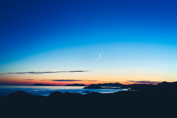 Wall Mural - landscape of a sunset over the sea with the two-quarter moon