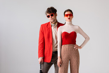 Wall Mural - fashionable couple in sunglasses looking at camera isolated on grey