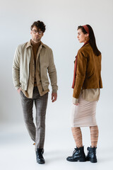Wall Mural - full length view of trendy couple posing on grey while man looking at camera on grey
