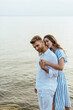 © LIGHTFIELD STUDIOS - attractive girlfriend hugging and holding hands with handsome boyfriend near river