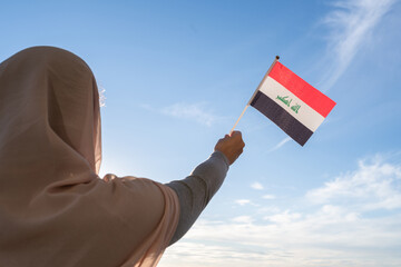 Poster - Silhouette of muslim woman in head scarf with Iraq flag at blue sunset sky. Concept of freedom