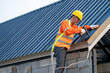 © visoot - Roofer using air or pneumatic nail gun and installing Metal Sheet on top new roof.