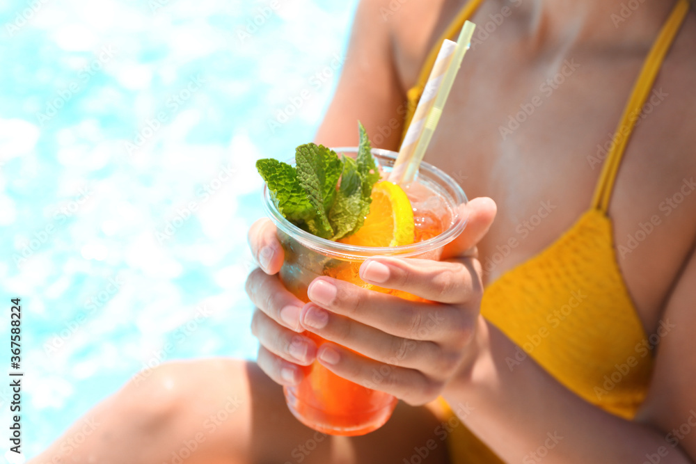 Woman with glass of refreshing drink near swimming pool, closeup - obrazy, fototapety, plakaty 