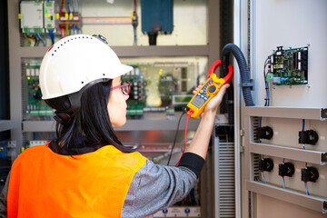 Young female maintenance engineer testing voltage with digital multimeter