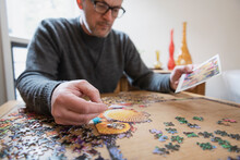Man Assembling Jigsaw Puzzle On Table At Home