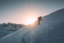Man Mountaineer With Trekking Pole Climbing On Snowy Hill And Sunshine At Ryten Mount