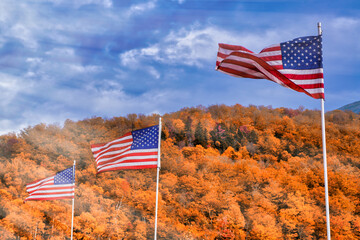 Waving american flags in New England, autumn foliage season with orange colors and blue sky