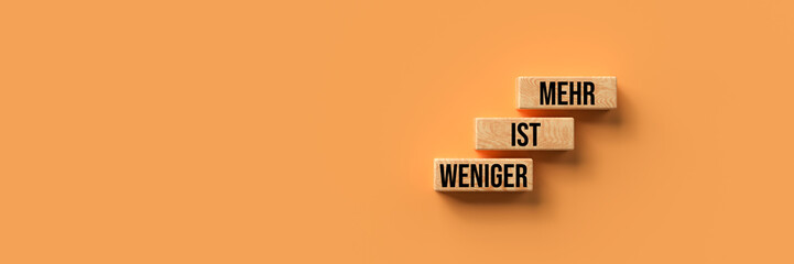 Wall Mural - cubes with German message for LESS IS MORE on orange background