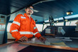 © Igor Kardasov - Filipino deck Officer on bridge of vessel or ship wearing coverall during navigaton watch at sea . He is plotting position on chart