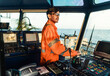 © Igor Kardasov - Filipino deck Officer on bridge of vessel or ship wearing coverall during navigaton watch at sea . He is maneuvering with cpp thrusters propulsion