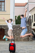 © danmorgan12 - Vacations Travel Ideas. Happy Caucasian Couple Having Fun and Jumping Together During City Traveling.