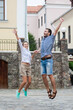 © danmorgan12 - Vacations Travel Ideas. Happy Caucasian Couple Having Fun and Jumping Together With Outstretched Hands During Traveling in The City.