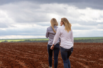 two females country farmer girls sisters walking on field