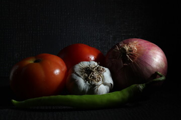 Green chilly, Garlic, Tomato, Onion and Curry leaf are isolated on black background. Ingridients concept. Hot and spicy green chillies and fresh ripe tomato, Onion on black background.