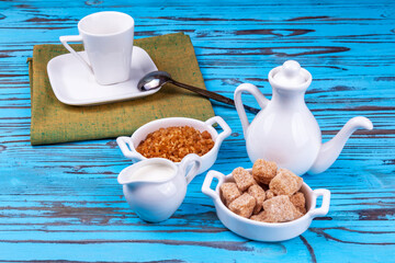 Table setting for coffee. Milk jug, coffee pot, and small saucers with cane sugar