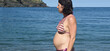   pregnant woman standing sunbathing on the beach