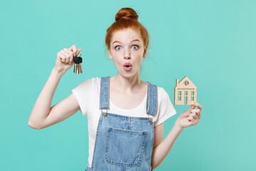 Wall Mural - Shocked young readhead girl in casual denim clothes isolated on blue turquoise wall background studio portrait. People sincere emotions lifestyle concept. Mock up copy space. Hold house bunch of keys.