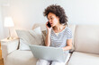 © Graphicroyalty - Woman sitting on sofa with laptop and talking on phone at home. Young successful businesswoman working from home while talking at phone. College student studying on laptop and using phone.