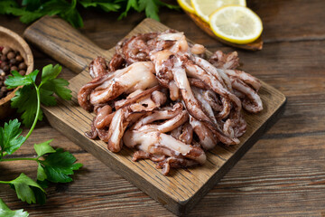 Wall Mural - The tentacles of squid. Raw squid tentacles on a wooden serving Board on a brown wooden kitchen table. Lots of squid tentacles