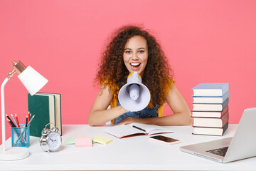 Canvas Print - Cheerful african american girl employee in office sit work at desk isolated on pink background. Achievement business career. Education in school university college concept. Screaming in megaphone.