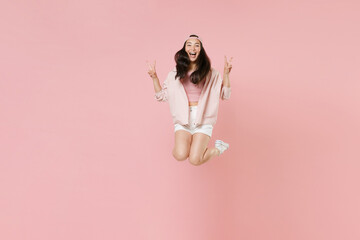 Wall Mural - Full length portrait of cheerful young asian girl in casual clothes, cap isolated on pastel pink background studio portrait. People lifestyle concept. Mock up copy space. Jumping showing victory sign.