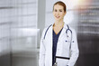 © rogerphoto - Cheerful female doctor standing in sunny clinic. Portrait of friendly smiling woman-physician. Medicine concept