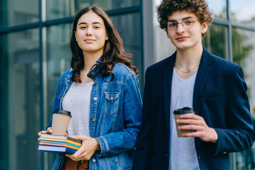 Young woman and man having fun together after classes, drinking coffee and having good time. Students in love holding books, exercise books, spend time together after attending lectures and seminars