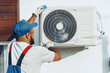 © fotofabrika - Repairman in uniform installing the outside unit of air conditioner