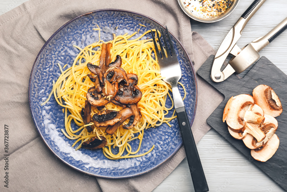 Plate with tasty pasta and mushrooms on table