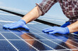 Male worker hands in glows on solar panel, technician installing solar panels on roof. Alternative energy sun energy power, ecological concept.