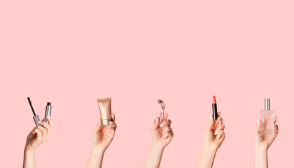 Women hands holding various cosmetic products on pink background, empty space. Creative collage
