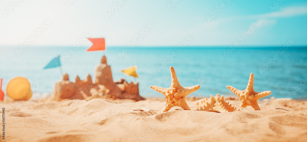 Sandcastle on the beach at sea in summertime - obrazy, fototapety, plakaty 