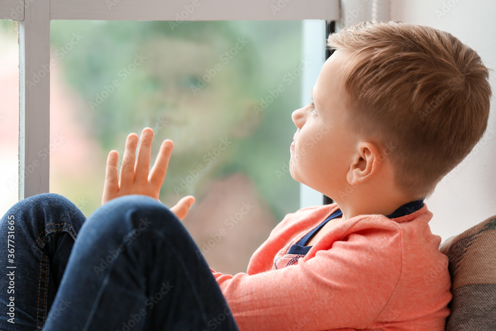 Little boy with autistic disorder sitting near window at home