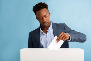 Wall Mural - African american man putting ballot in election box over blue