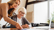 © InsideCreativeHouse - Insurance agent standing in front of laptop and giving advise to senior woman.