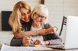 © InsideCreativeHouse - Adult daughter helping senior woman complete form at home