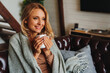 © InsideCreativeHouse - Close up of dreaming middle aged woman sitting in living room with cup of coffee or tea enjoying under blanket