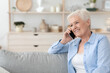 © Prostock-studio - Smiling senior lady talking on cellphone while relaxing on couch at home