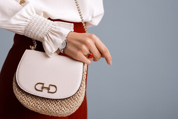 Close up of fashionable elegant woman`s outfit: trendy small  shoulder bag, stylish wrist watch, beautiful ring with red gem. Copy, empty space for text
