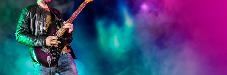 Guitar player performs on stage. Rock guitarist plays solo on an electric guitar. Artist and musician performs like rockstar. Black and white version. Green and pruple version. Panoramic image.