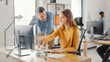 © Gorodenkoff - Female Specialist Works on Desktop Computer, Project Manager Stands Beside and gives Advice on Optimizing Workflow for Customer Experience Management. Modern Office with Diverse Team of Professionals