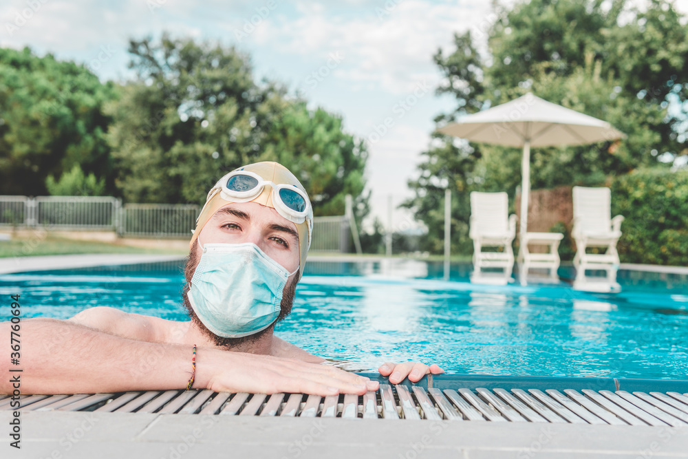 Handsome young man inside the pool with his mask on. He's wearing his ...