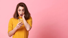 Happy And Surprise Young Woman Good Looking Using Mobile Phone On Pink Copy Space Background.