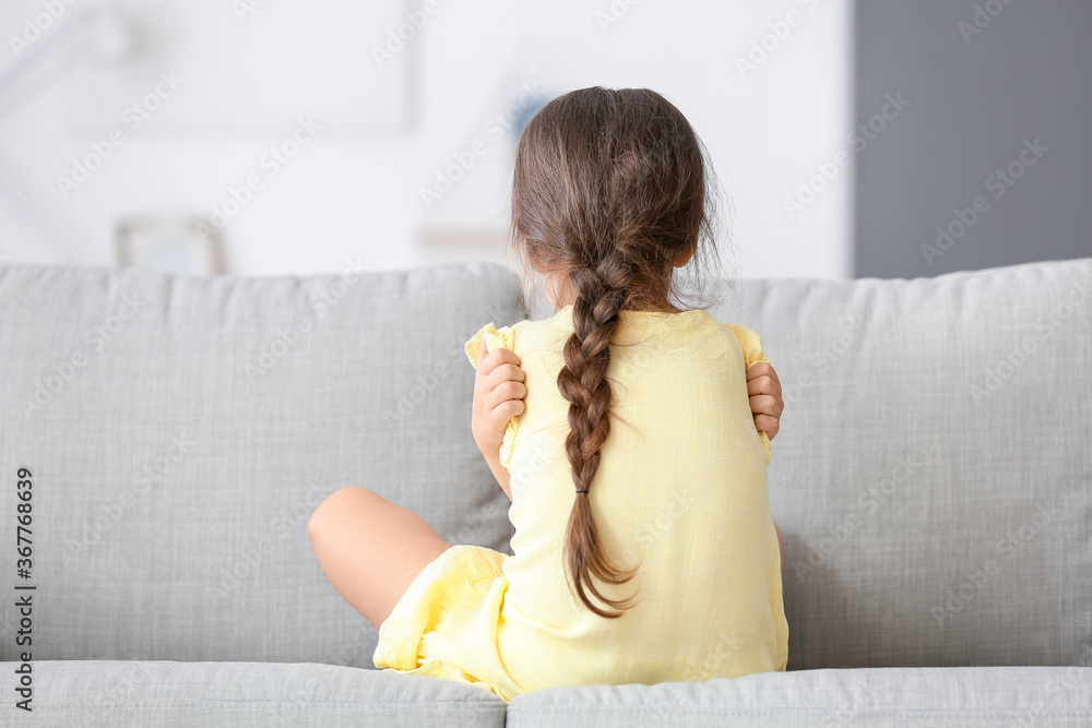 Sad little girl with autistic disorder at home, back view