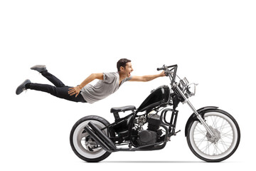 Wall Mural - Young man flying and holding on to a chopper motorbike