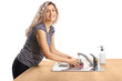 © Ljupco Smokovski - Smiling young woman washing a plate in a stainless steel sink