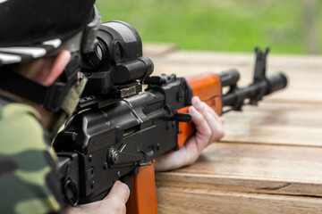 Poster - Military shooter with his precising assault rifle aiming and shooting target in the range