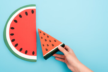 Sticker - partial view of female hand with paper watermelon slices on blue background