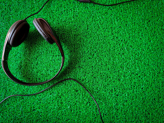 Black wired headphone isolated on green background. Copy space